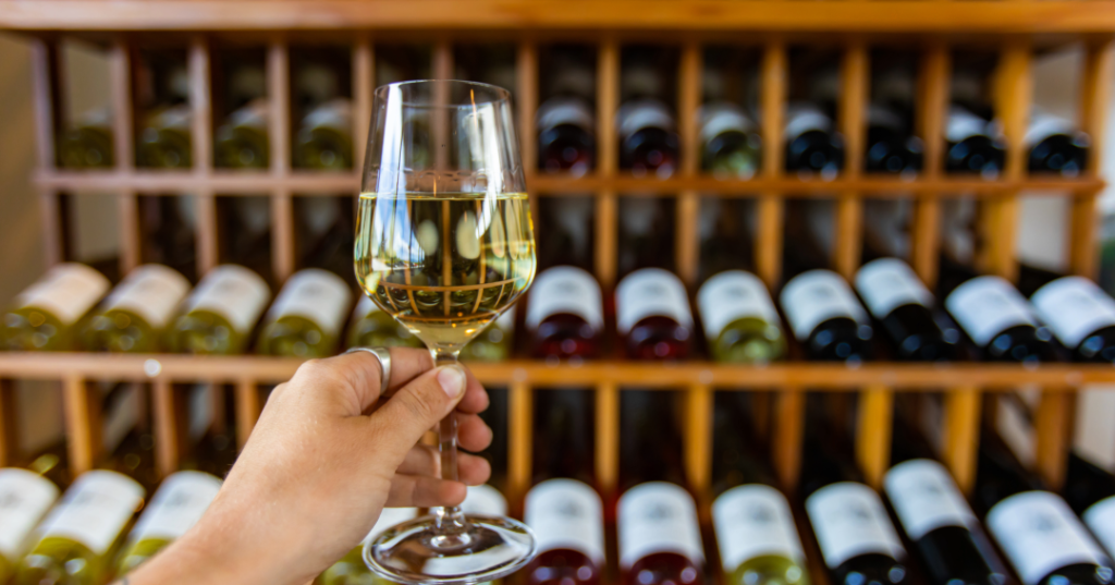 a glass of wine infront of a wine collection