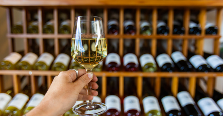 a glass of wine infront of a wine collection