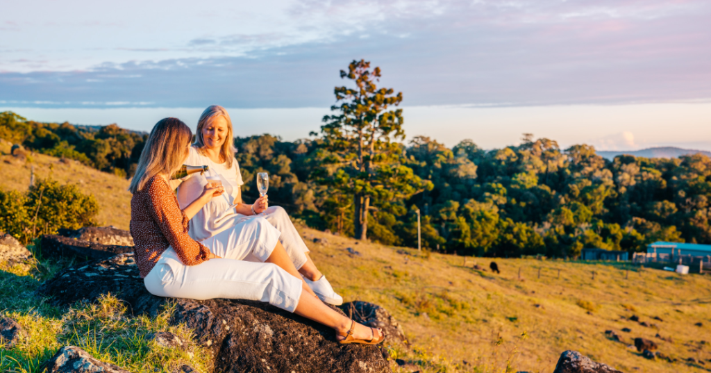two ladies pouring prosecco on a hill overlooking the hinterlands