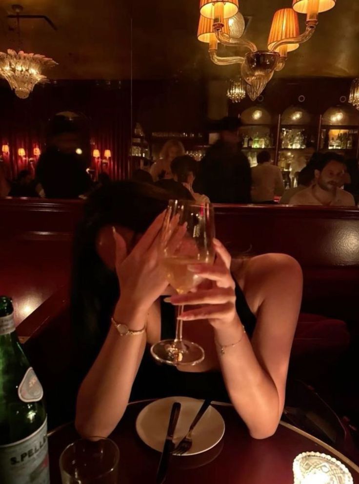 Woman covering her face with her hand and cheersing her wine glass at restaurant