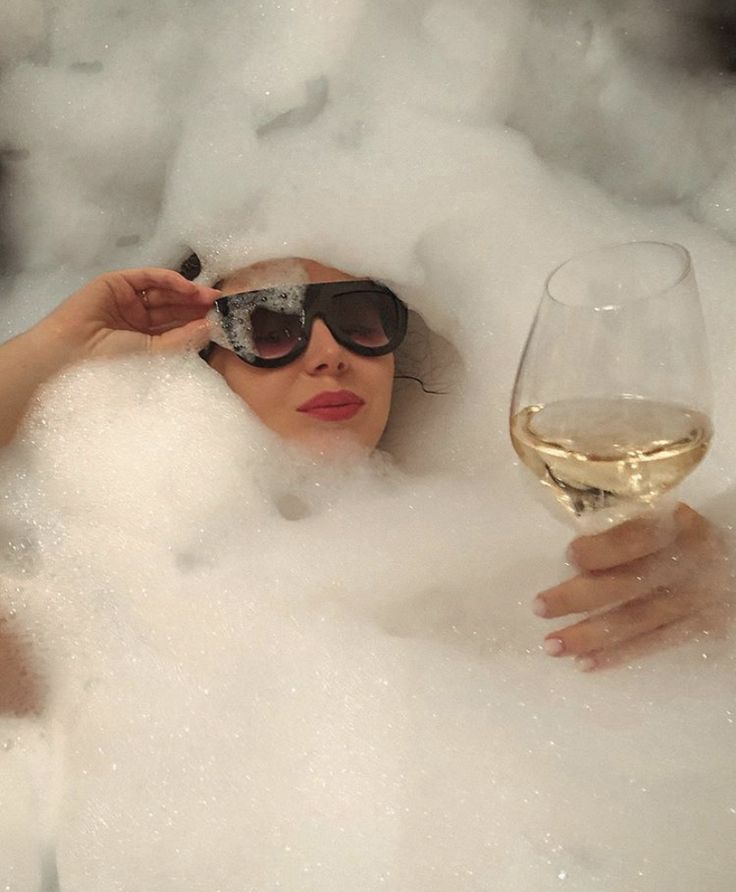 Woman in bubble bath with glass of wine in hand